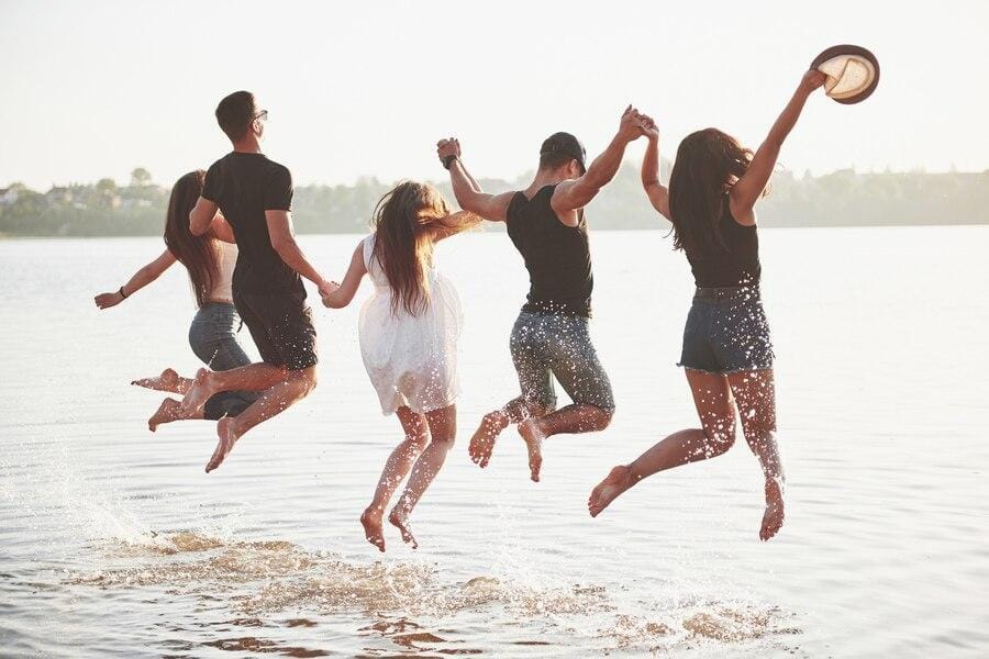 Photo from the back of five people jumping in the water