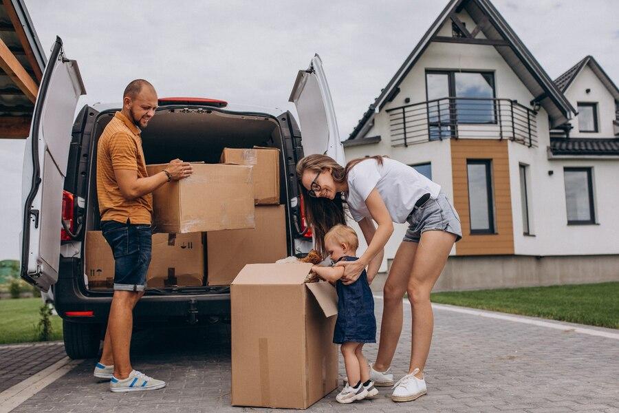 Parents unpacking moving van in front of the home with a toddler