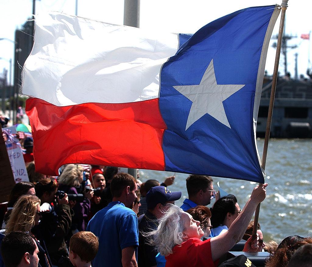 Texas state flag held by a woman by the water